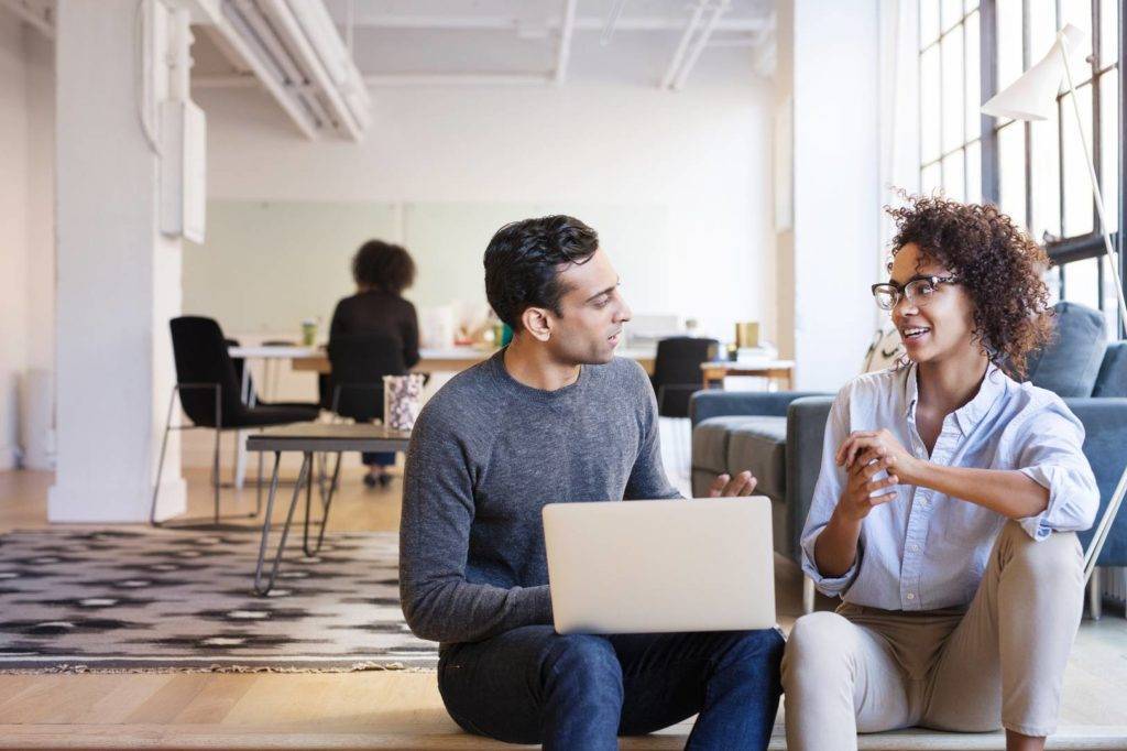 Two colleagues discussing next to laptop