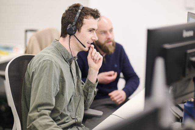 IT engineer at Ekco helping a customer on the phone and via their computer